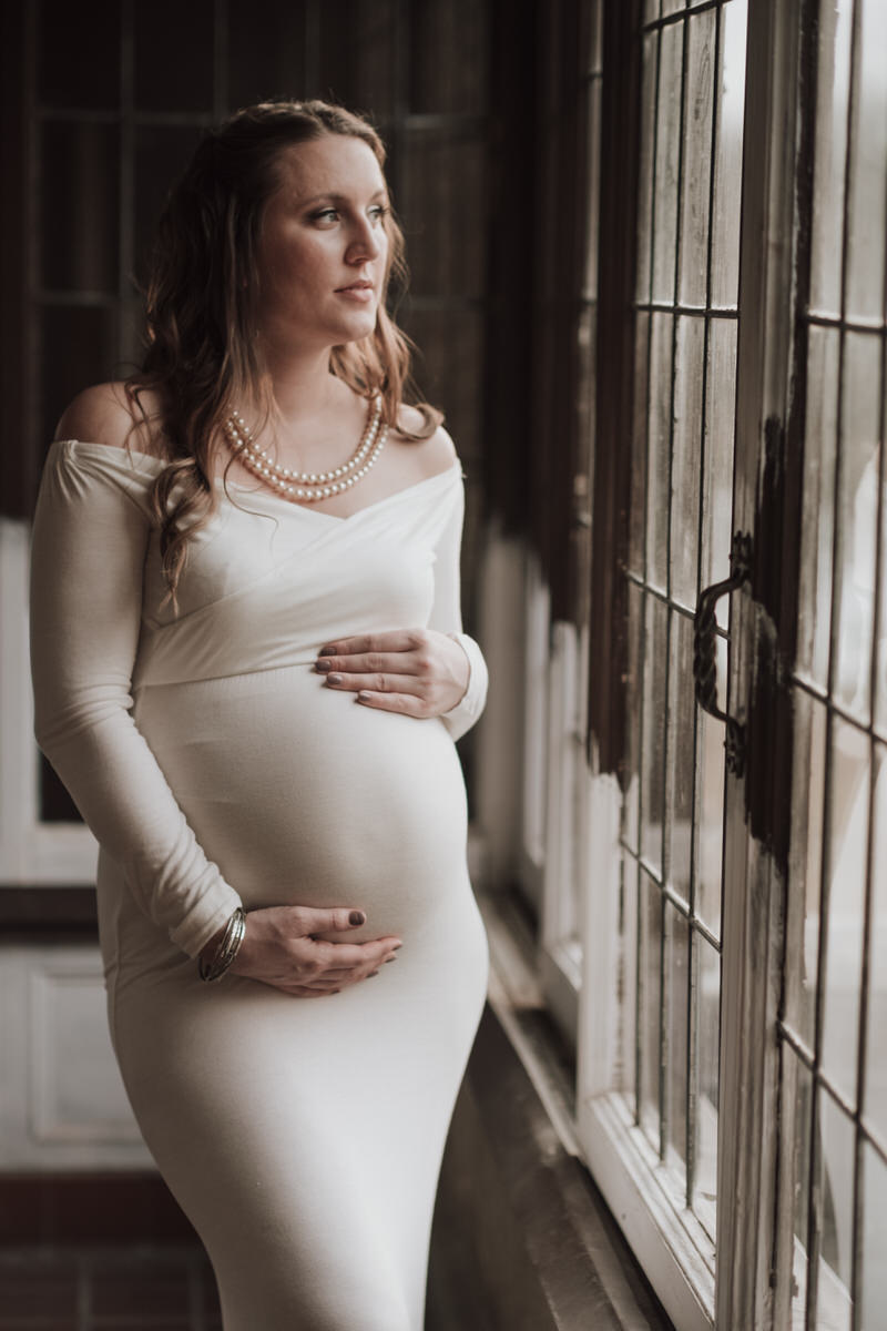 pregnant woman in white dress by window