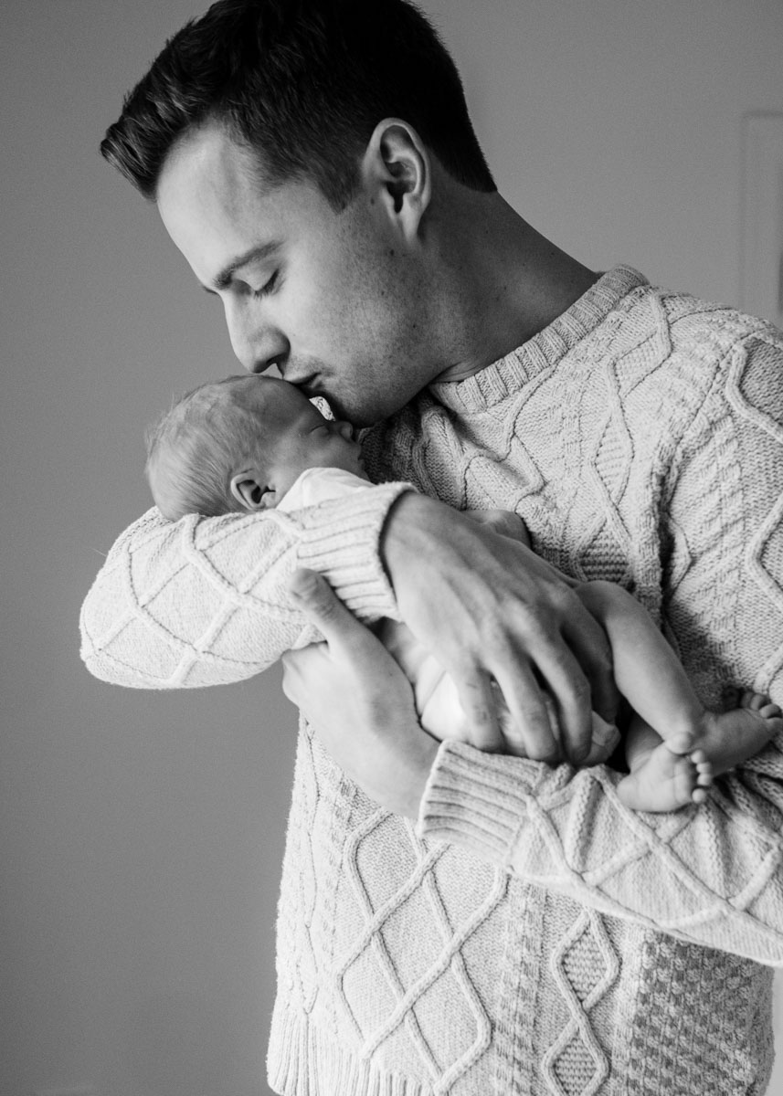 a dad leans in to kiss his newborn son