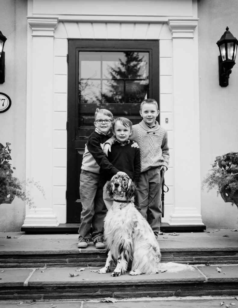 three brothers posing on front porch with dog