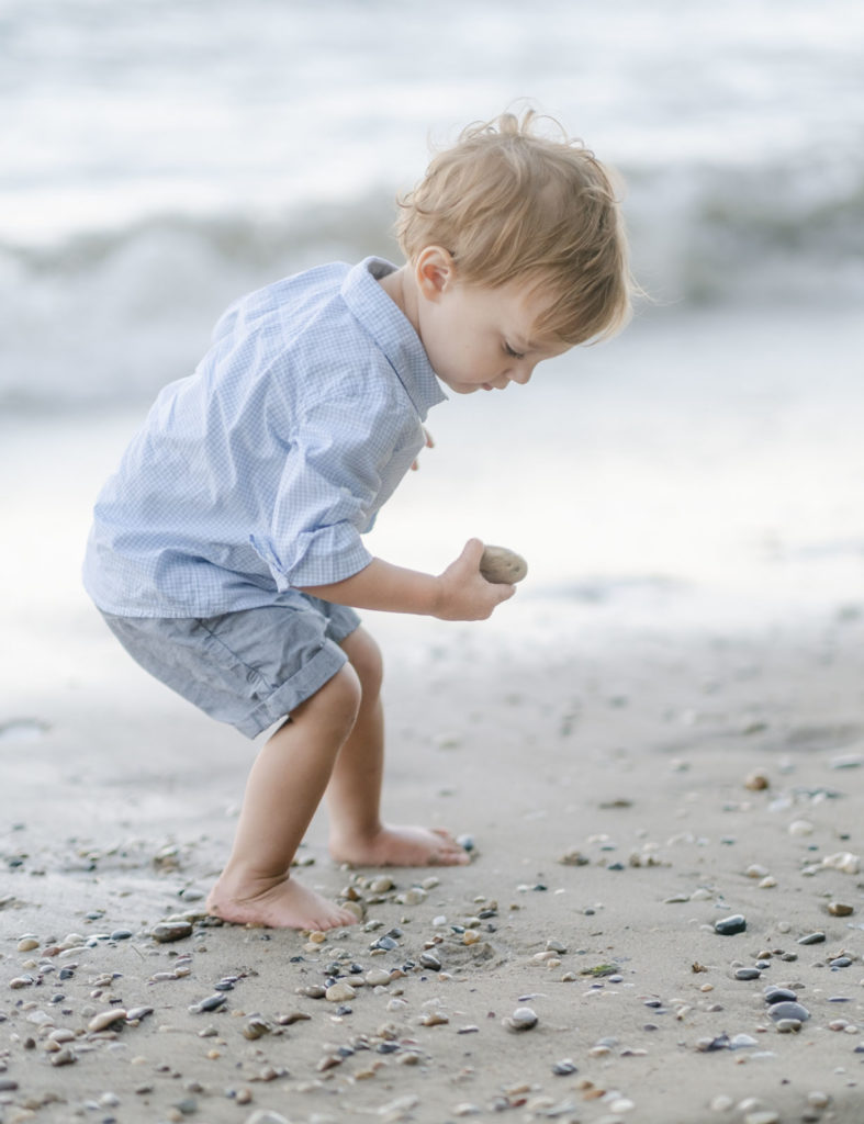a little boy picks up a rock during his glenview family photography shoot