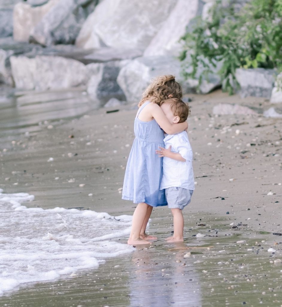 a brother and sister hug on the beach