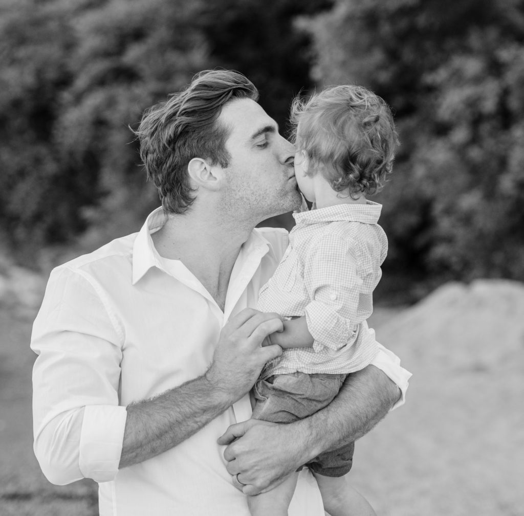 a dad kisses his young son on the cheek