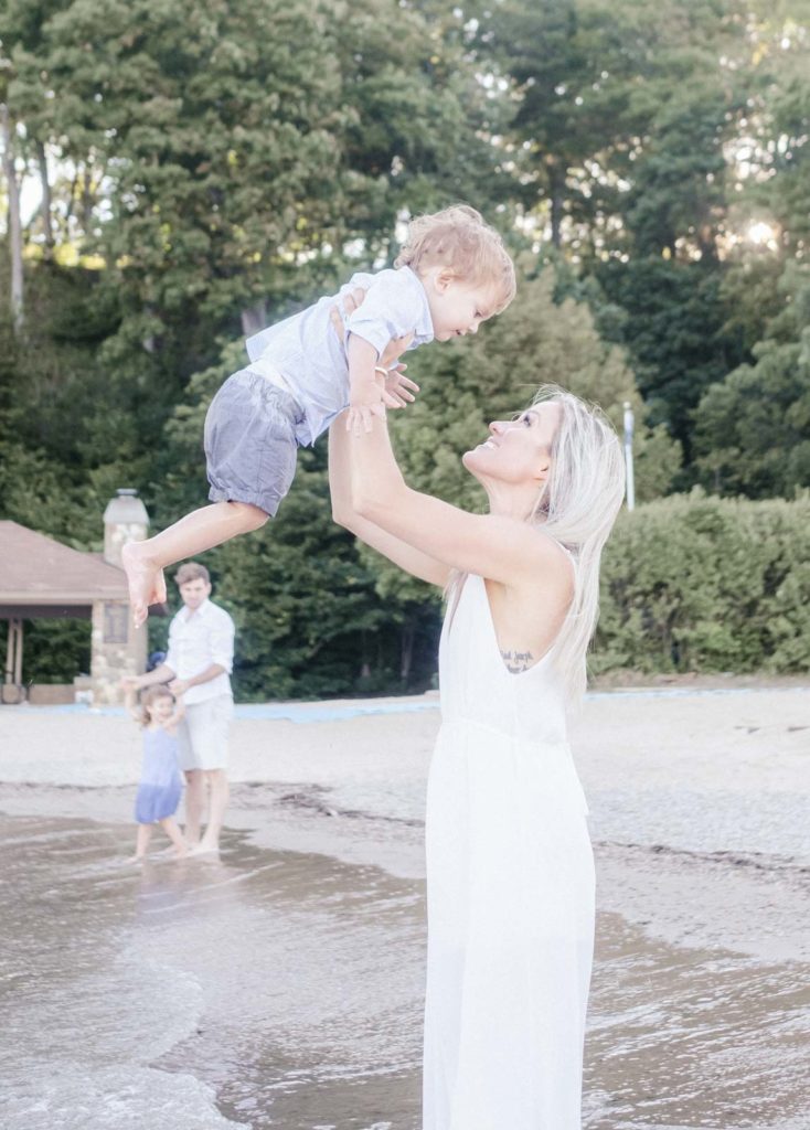 a mom throws her son into the air while they play on lake bluff beach